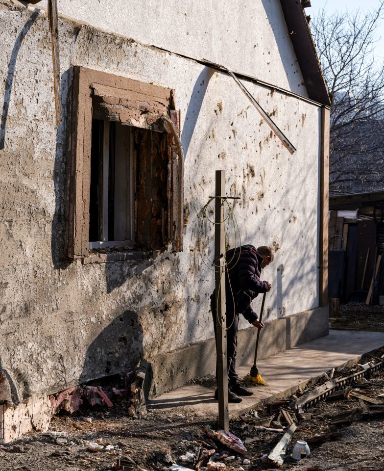 A man sweeps up rubble after shelling by Russian forces in Nivky, Kyiv, Ukraine